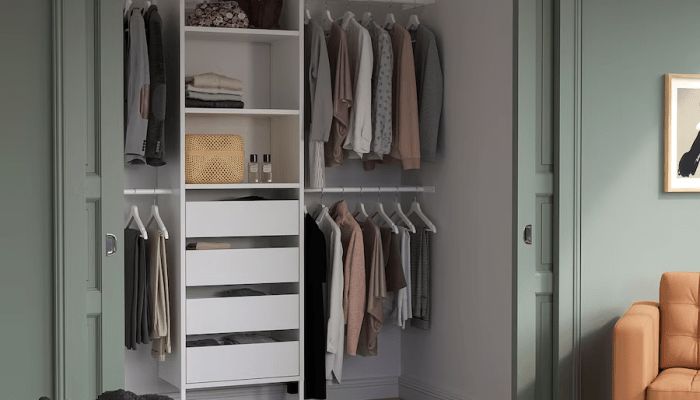 an open closet with clothes hanging on shelves and a couch in the corner next to it