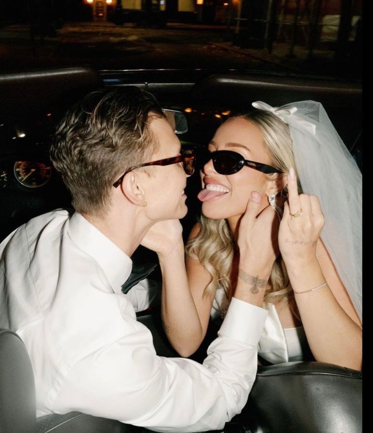 a bride and groom are sitting in the back seat of a car, smiling at each other