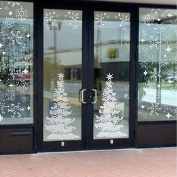 a glass door with snowflakes on it and a christmas tree in the window