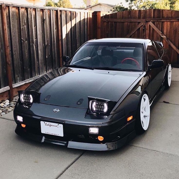 a black car parked in front of a wooden fence