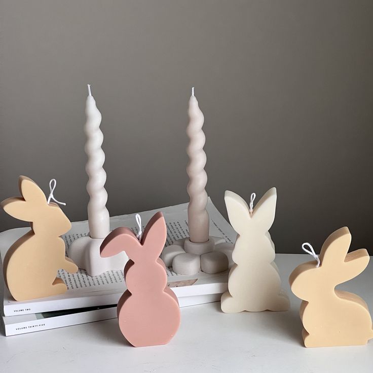 some bunny candles are sitting next to each other on a table with an open book