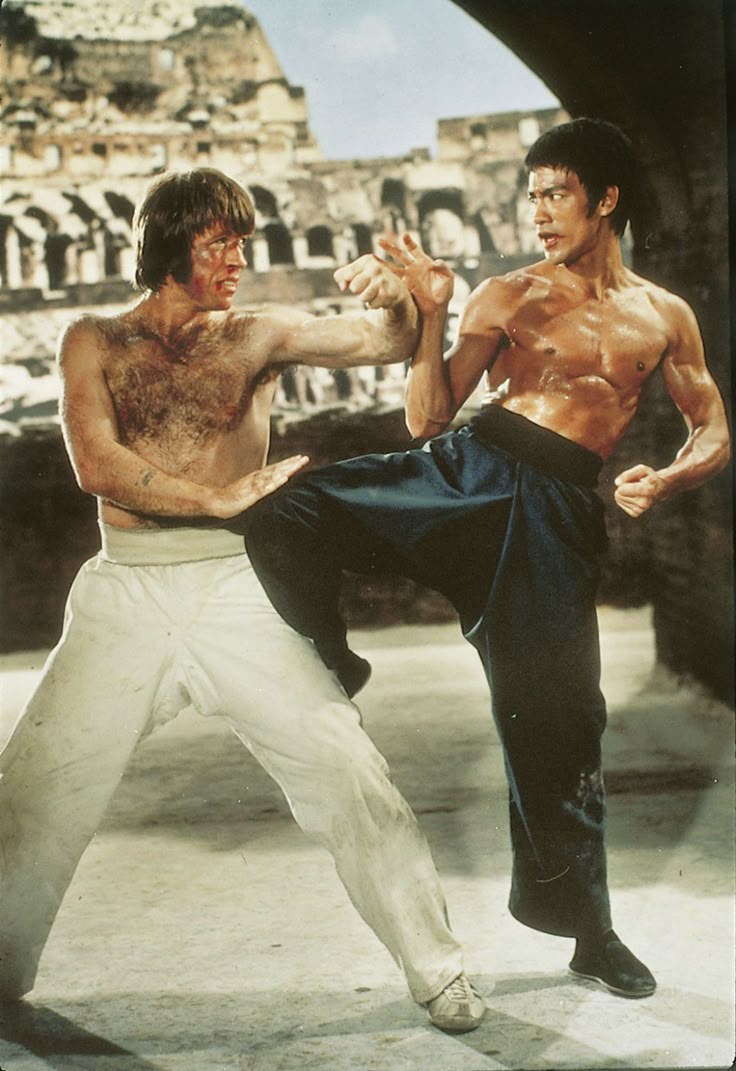 two men doing karate moves in front of an old building with ruins on the other side