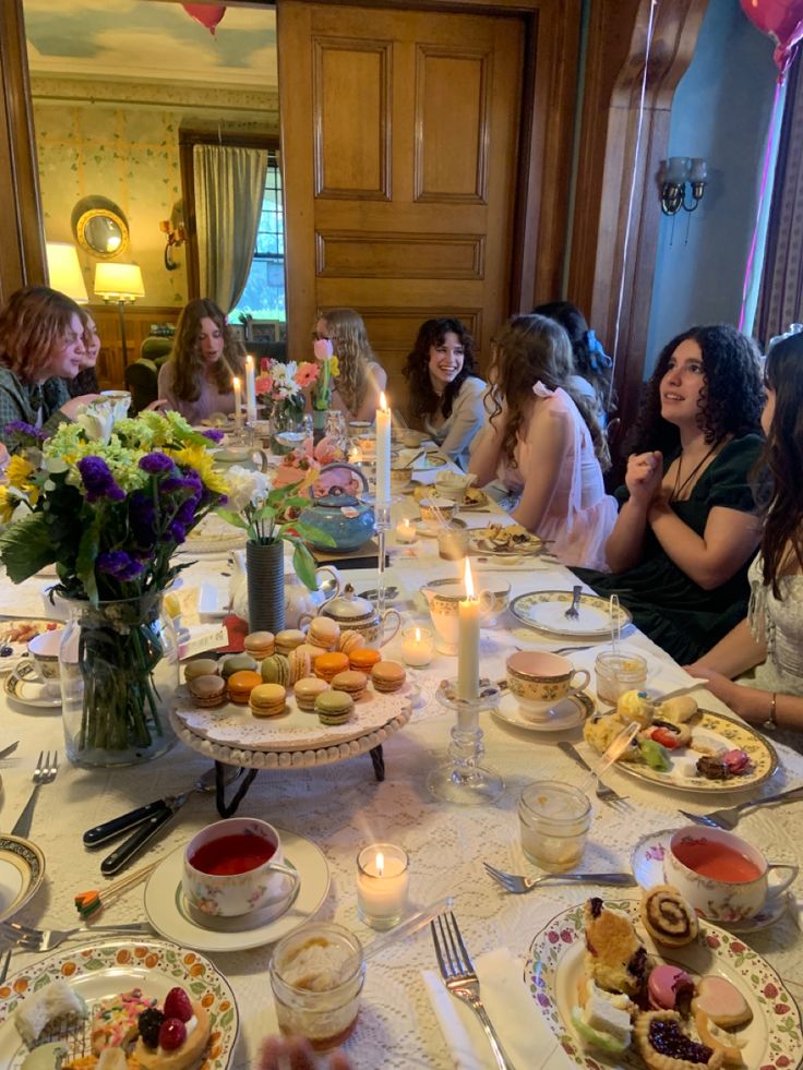 a group of people sitting around a table with plates and cups full of food on it