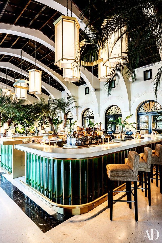 the interior of a restaurant with palm trees in the background and lights hanging from the ceiling