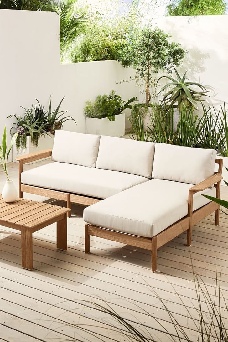 a couch and table on a deck with potted plants