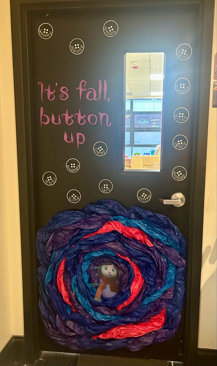 a door decorated with yarn and an image of a person in the center, saying it's fall button up