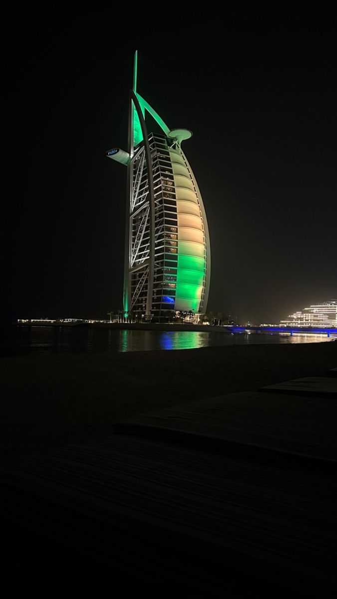 the bur is lit up in green and white at night, with other buildings behind it