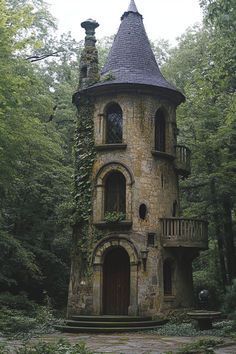 an old stone tower in the woods with ivy growing on it's roof and balcony