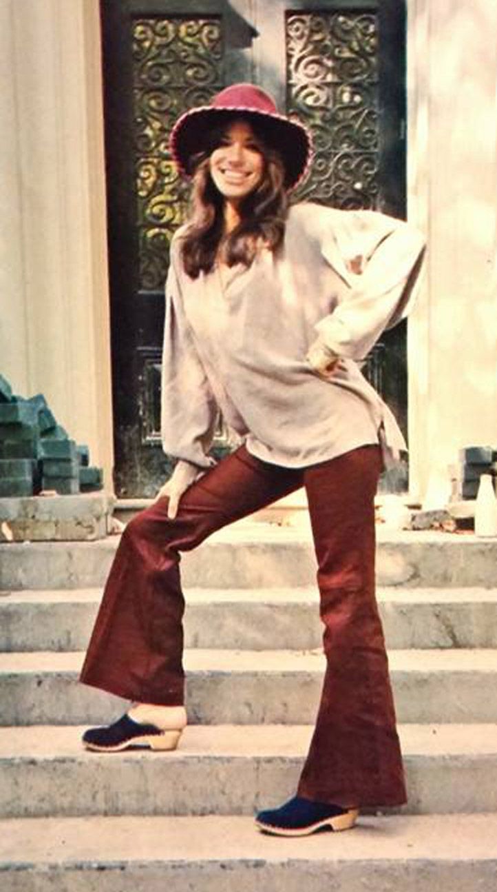 a woman is standing on some steps wearing a hat and bell - bottomed pants