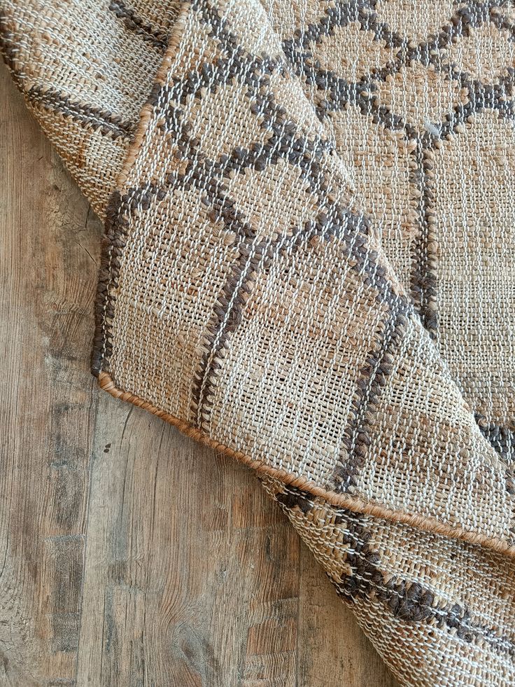 a close up view of a rug on a wooden floor with the fabric pulled back