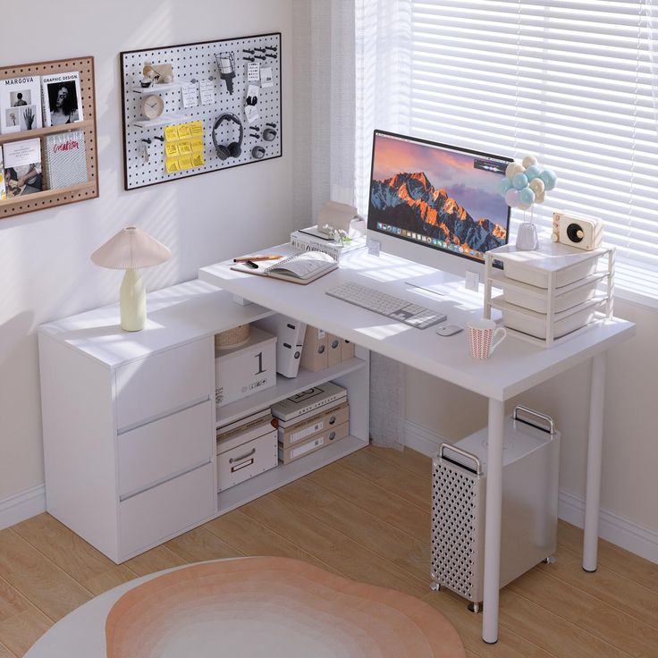 a white desk with a computer on top of it next to a lamp and pictures