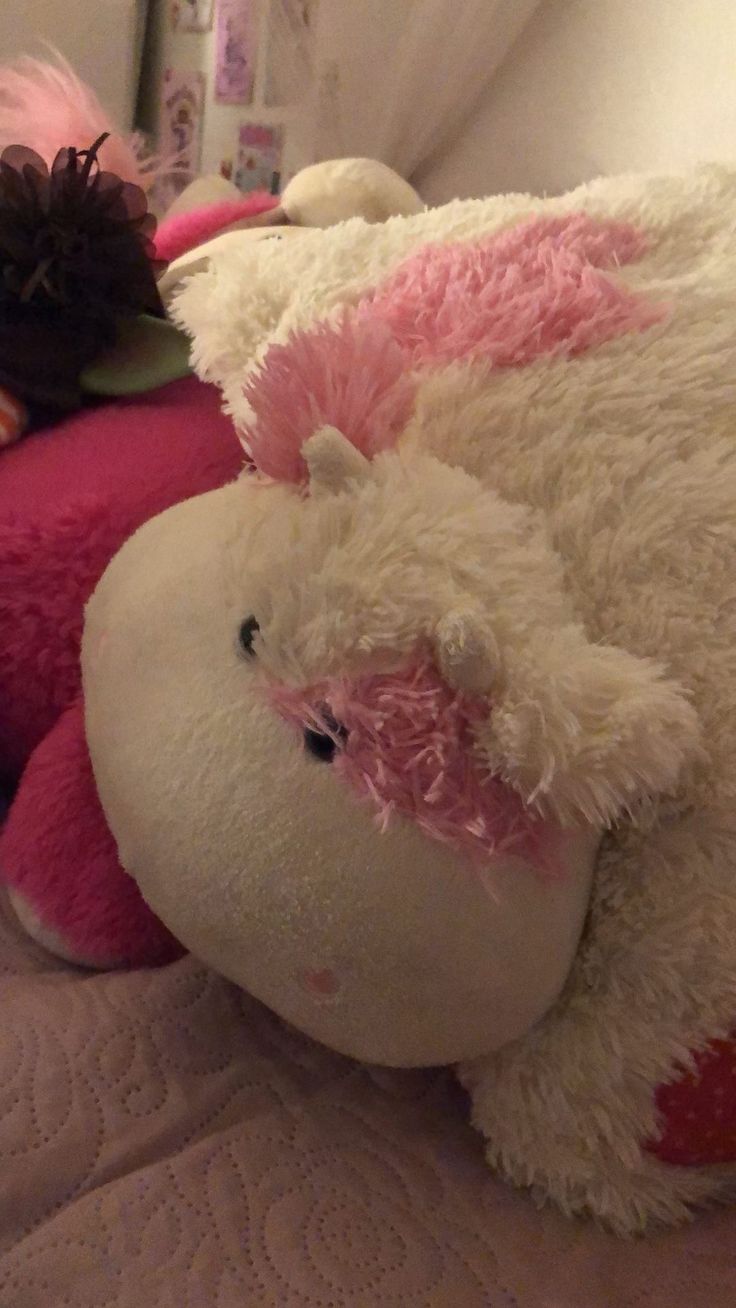 two large stuffed animals laying on top of a bed with pink and white furs