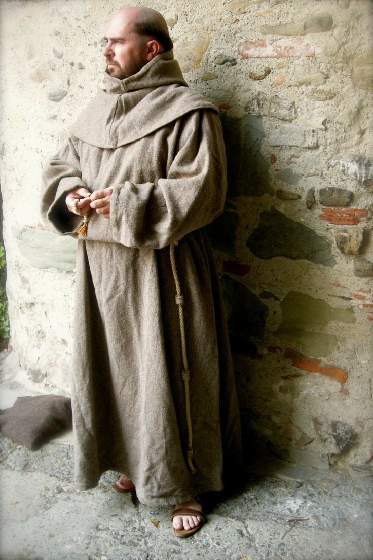 a man in a robe standing next to a wall with his hands on his hips