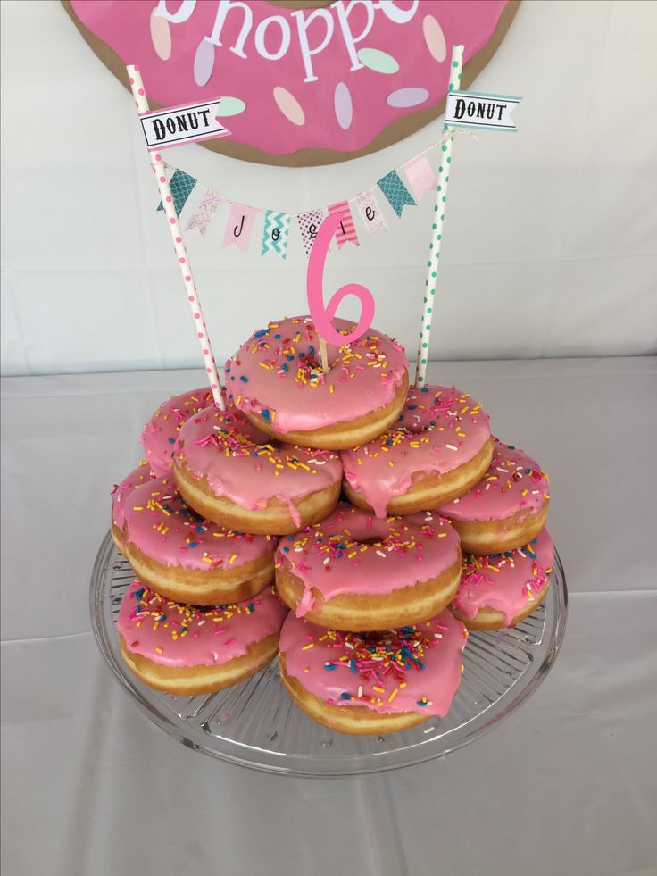 a plate full of donuts with pink frosting and sprinkles on it