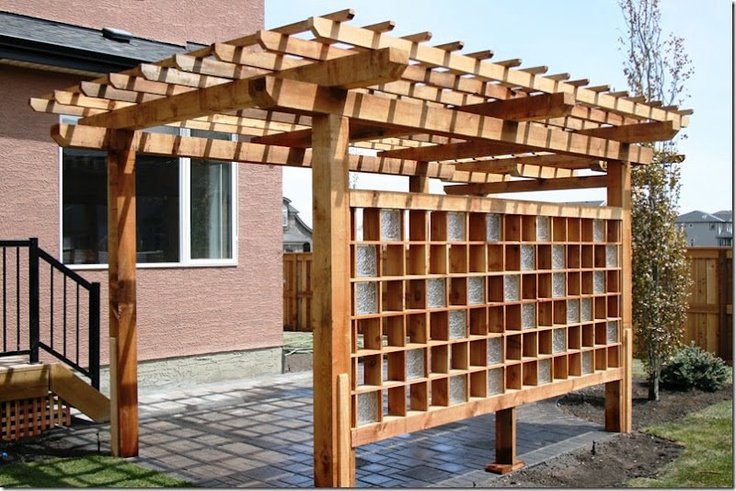 a wooden pergolan sitting in the grass next to a building