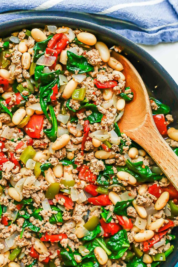 a skillet filled with ground beef, peppers, and green beans on top of a blue towel