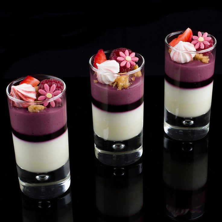 three glasses filled with desserts sitting on top of a black table next to each other