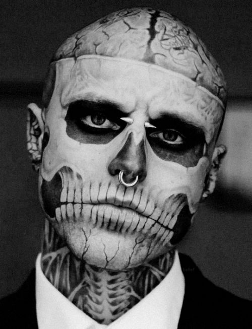 black and white photograph of a man with skeleton face paint on his head, wearing a tuxedo