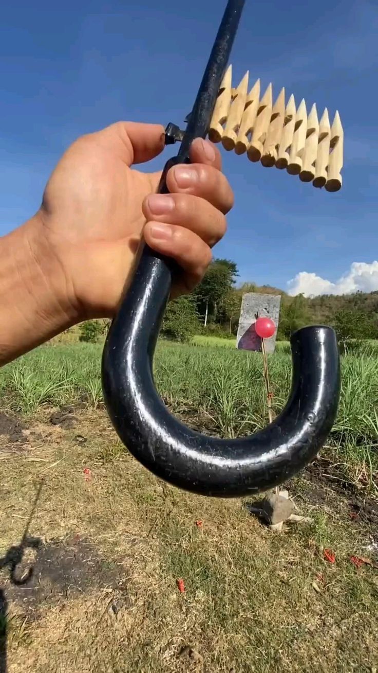 a hand holding an object in the air with it's long black handle and bent end