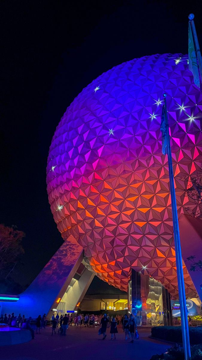 the spaceship shaped building is lit up with purple and blue lights in front of it