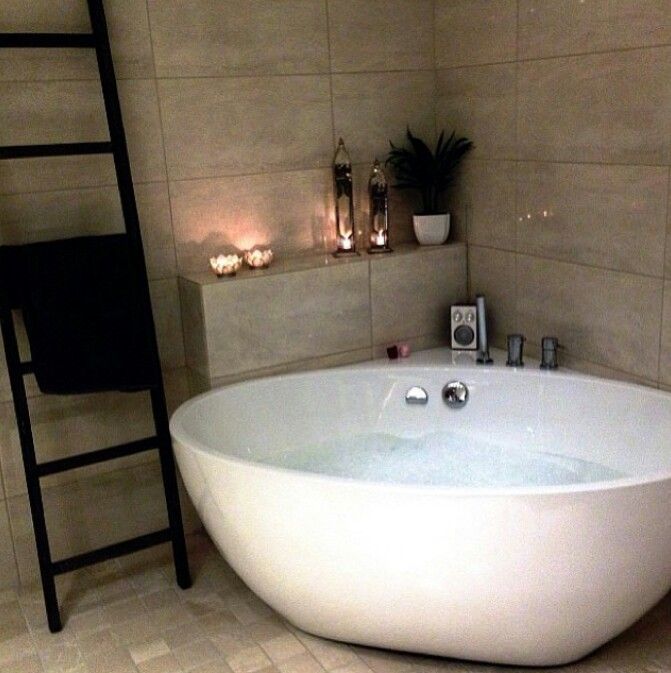 a large white bath tub sitting in a bathroom next to a ladder with candles on it