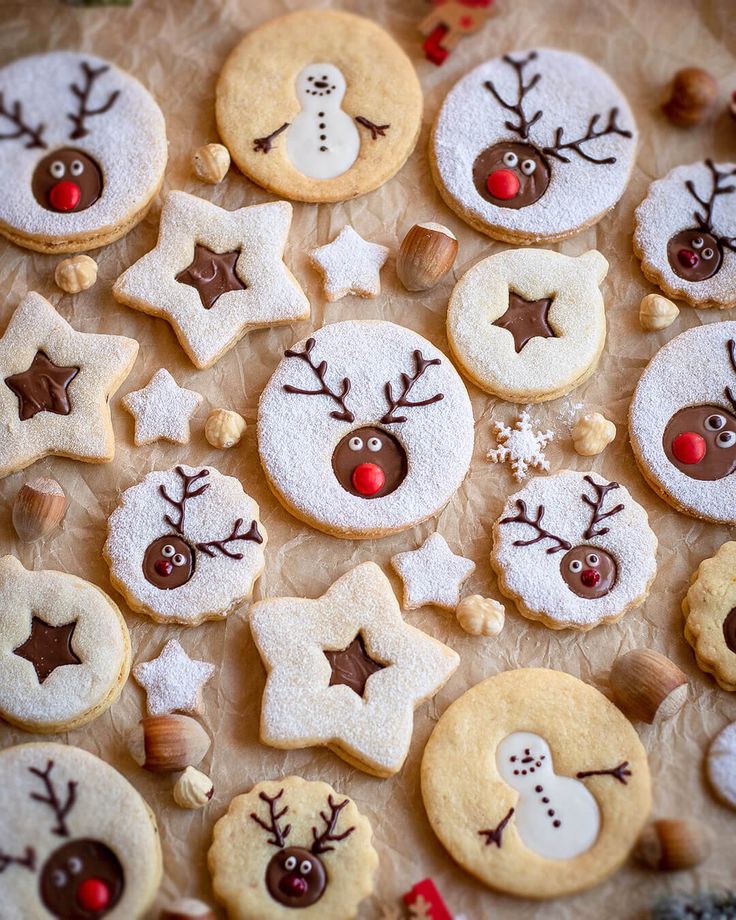 cookies decorated with reindeer, snowmen and stars are arranged on a sheet of wax paper