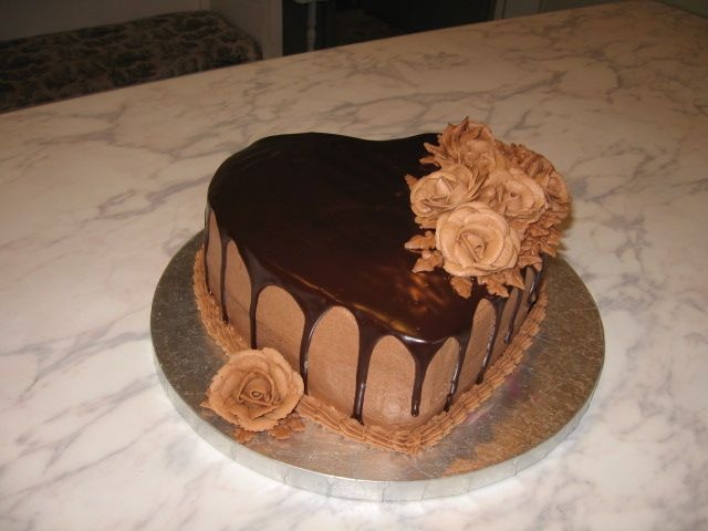 a heart shaped chocolate cake with flowers on it sitting on a counter top next to a knife