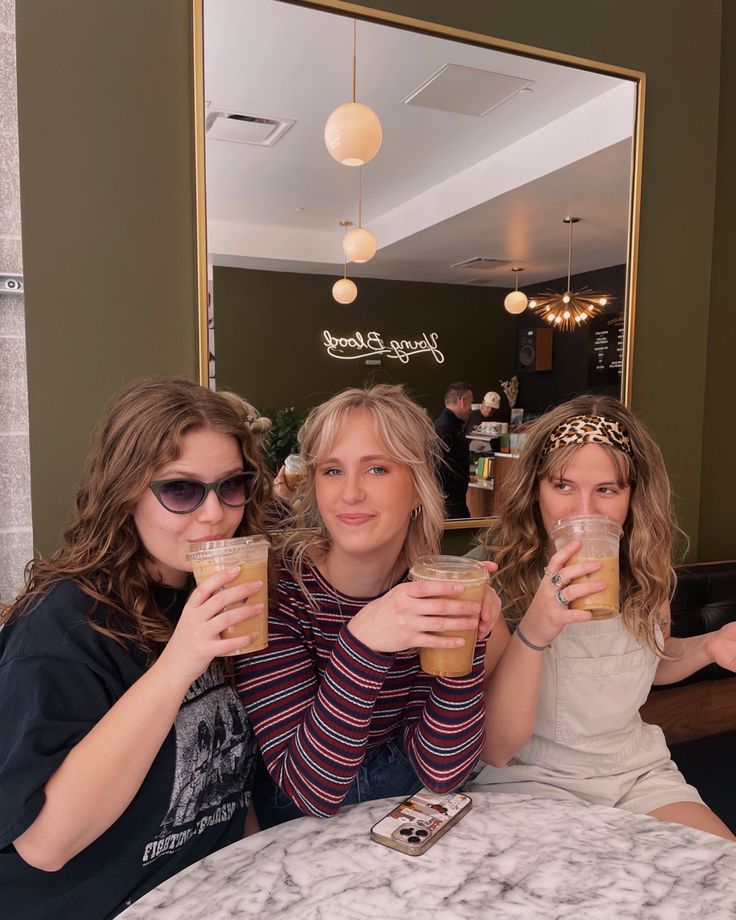 three women sitting at a table with drinks