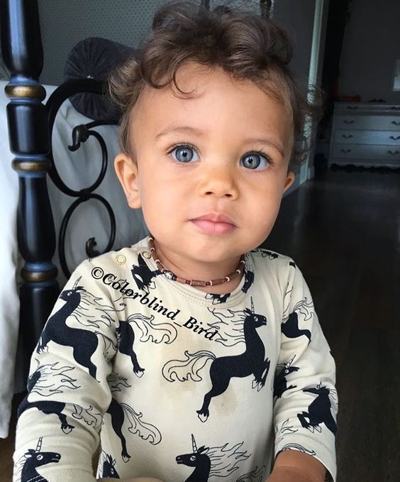 a little boy with blue eyes sitting in a chair