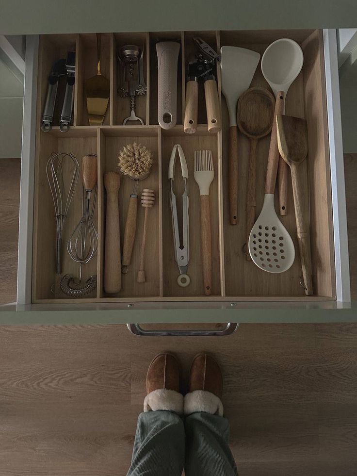 a drawer with utensils, spoons and spatulas in it on the floor