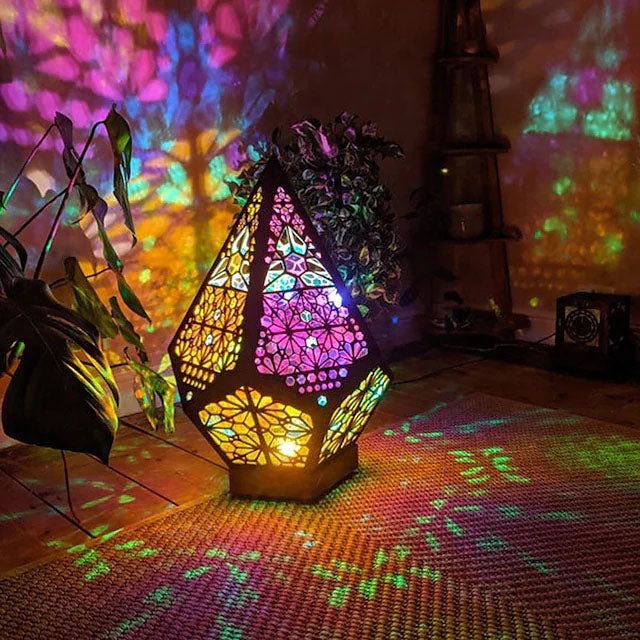 a lamp that is sitting on the floor in front of a wall with lights projected on it