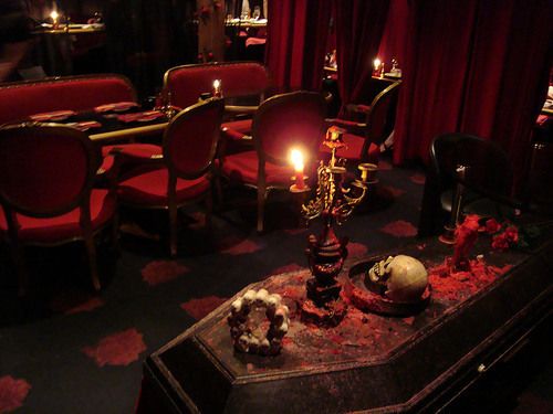 a table with candles on it in a room filled with red chairs and other furniture