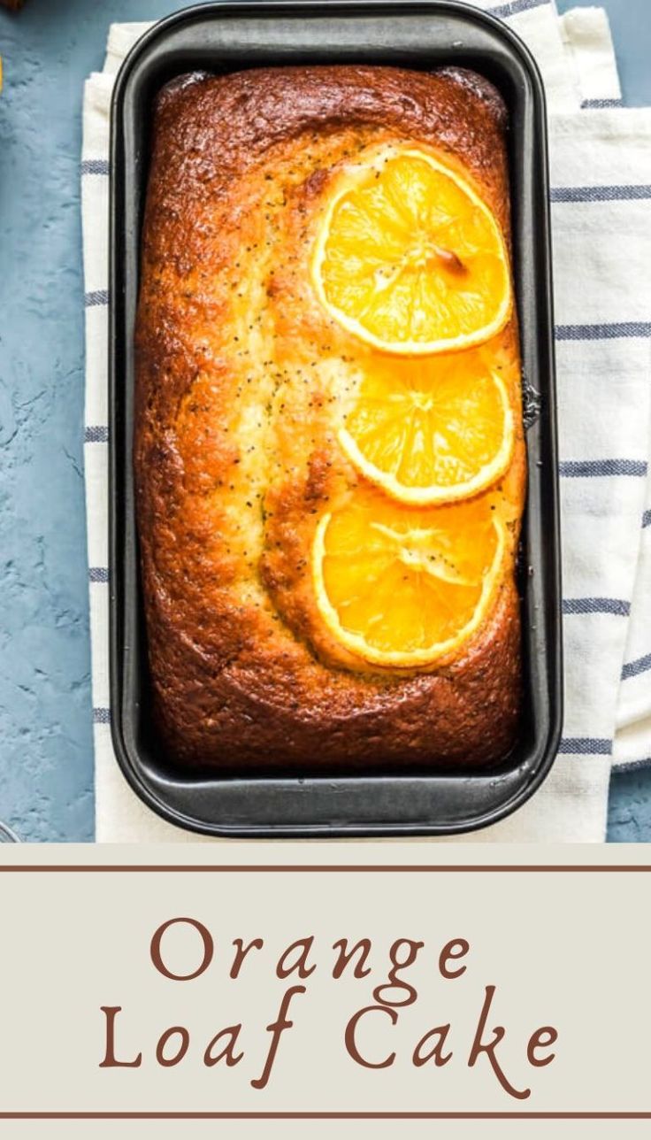 an orange loaf cake in a pan on top of a towel next to sliced oranges