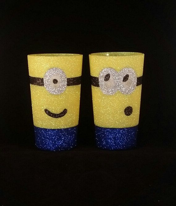 two yellow cups with faces painted on them are sitting side by side in front of a black background