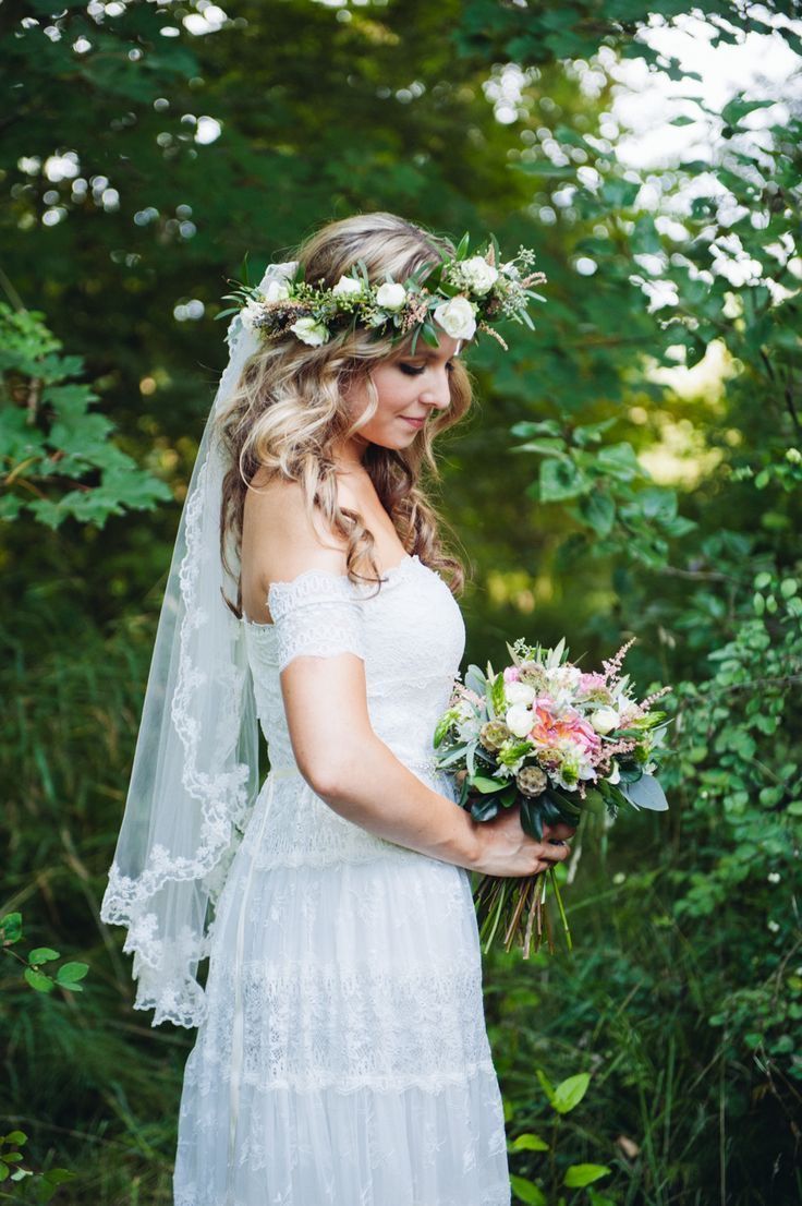 a woman in a white dress holding a bouquet and wearing a veil with flowers on her head