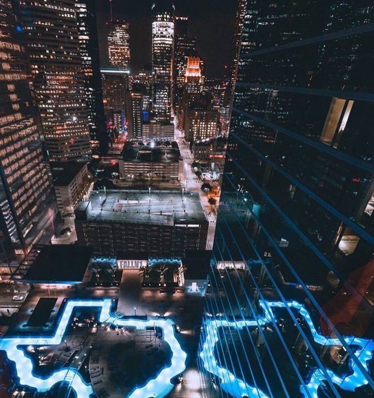 an aerial view of a city at night with blue lights on the streets and buildings