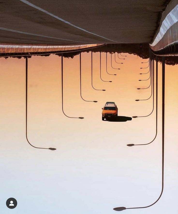 a reflection of a car in the water under a bridge at sunset or sunrise with street lights