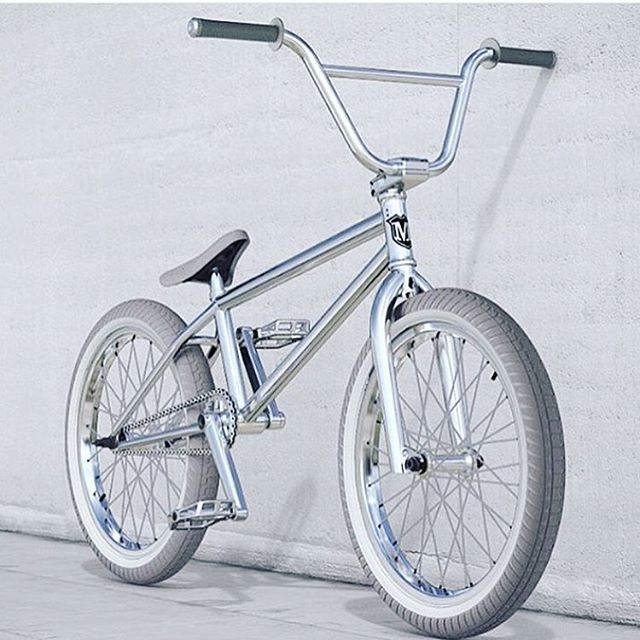 a silver bike leaning against a wall with no wheels on it's rims