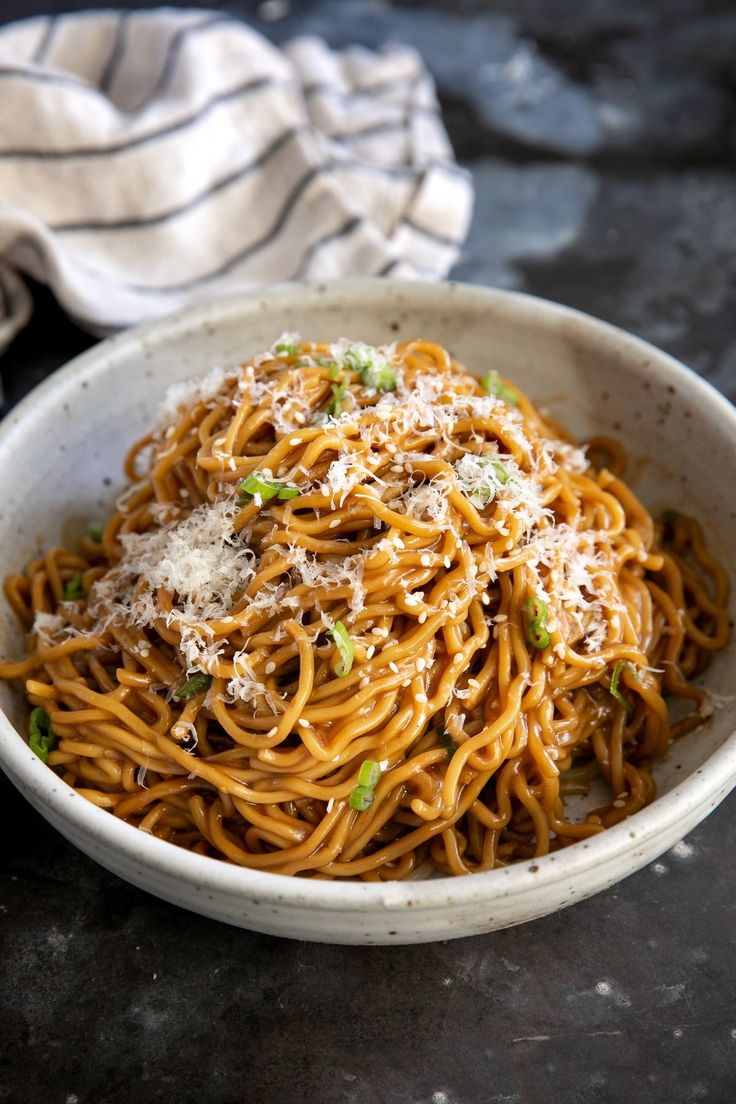 a white bowl filled with pasta and parmesan on top of a black table