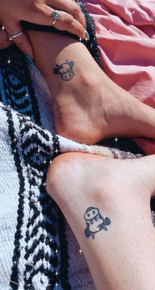 two people with matching tattoos on their feet sitting next to each other and holding hands