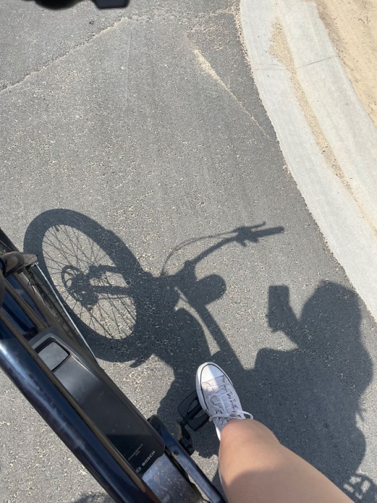 the shadow of a person's feet on a bike