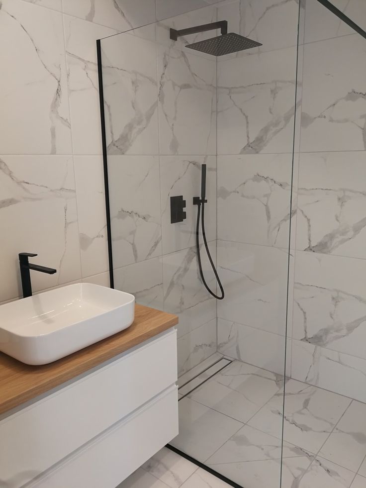 a bathroom with a sink, shower and stand up shower head in it's corner