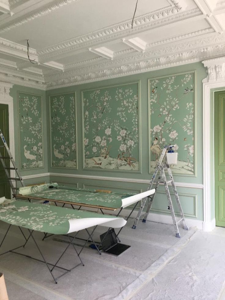 an empty room with green wallpaper and white trim on the walls is being worked on