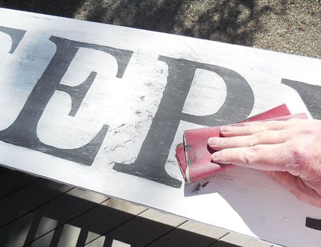 a person using a sponge to paint a sign