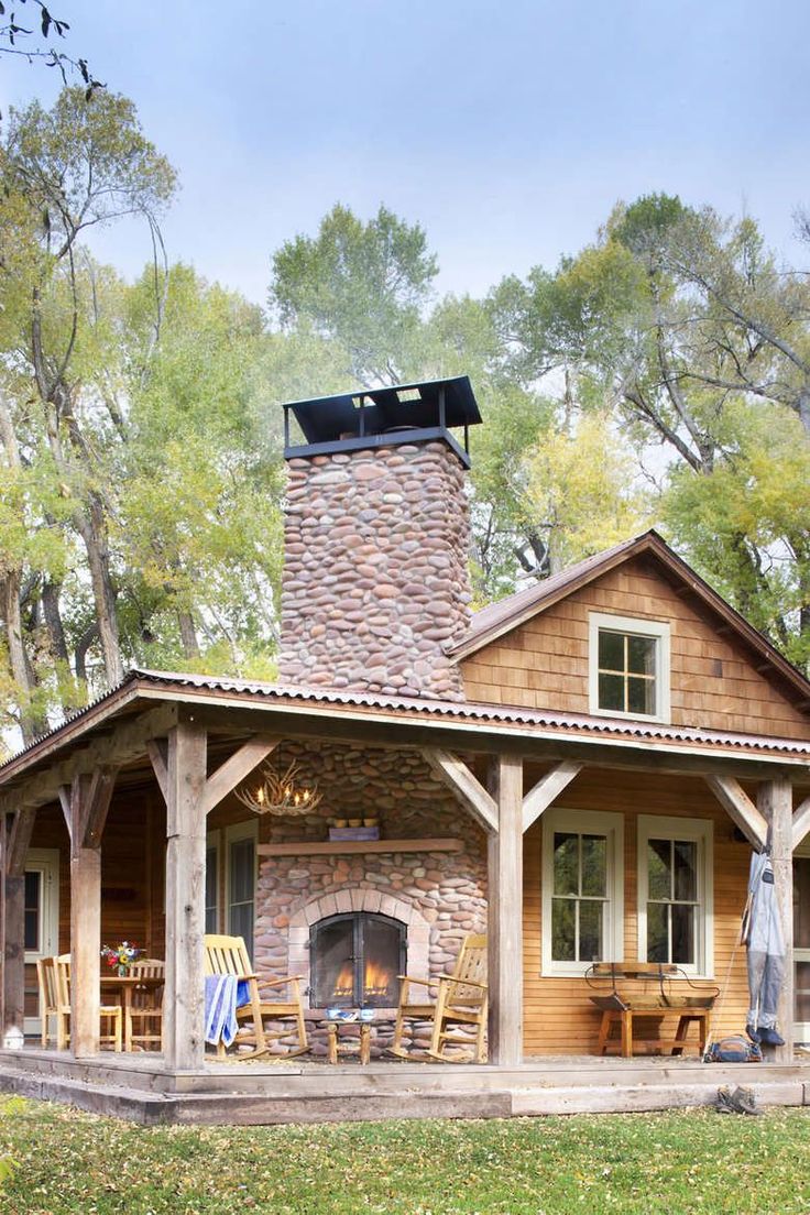 a small wooden cabin with a stone fireplace and covered patio area in the foreground