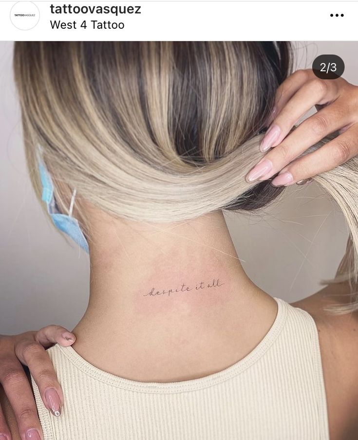 a woman's back neck with the word tattoo on her left side ribcage