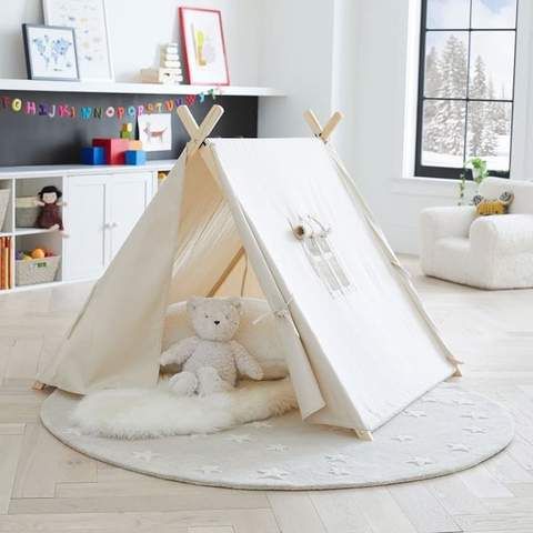 a child's teepee with a teddy bear in it and other toys on the floor