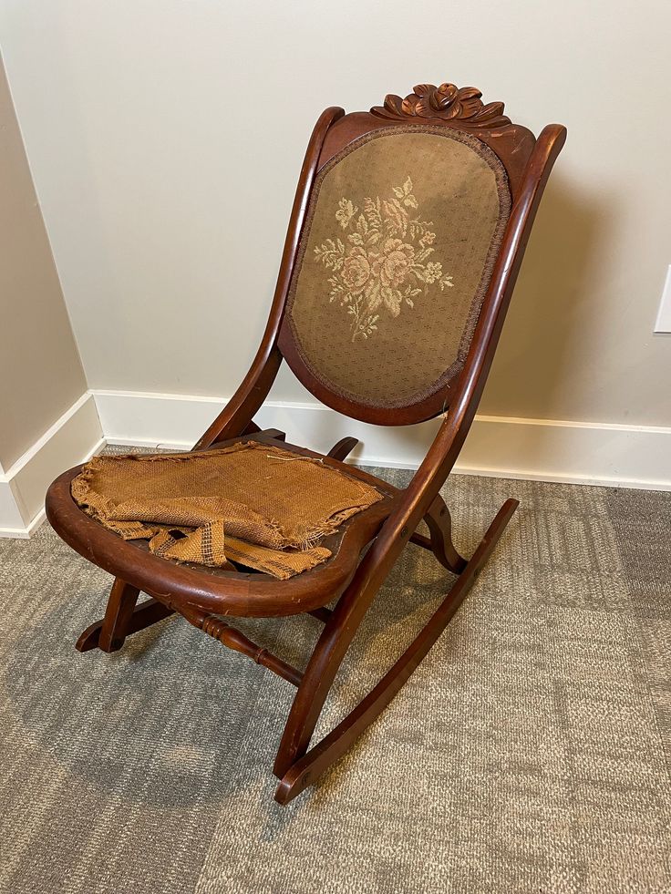 a wooden rocking chair sitting on top of a carpeted floor next to a wall