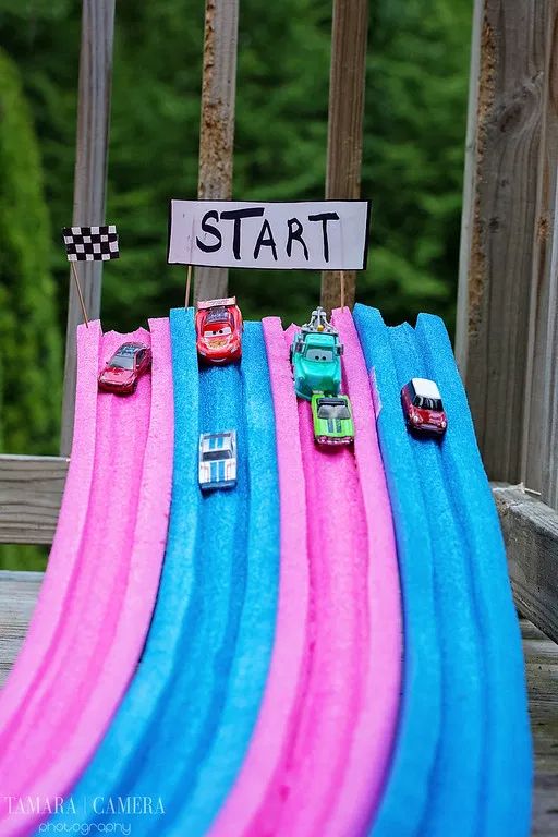 cars are lined up on top of blue and pink surfboards with a sign that says start