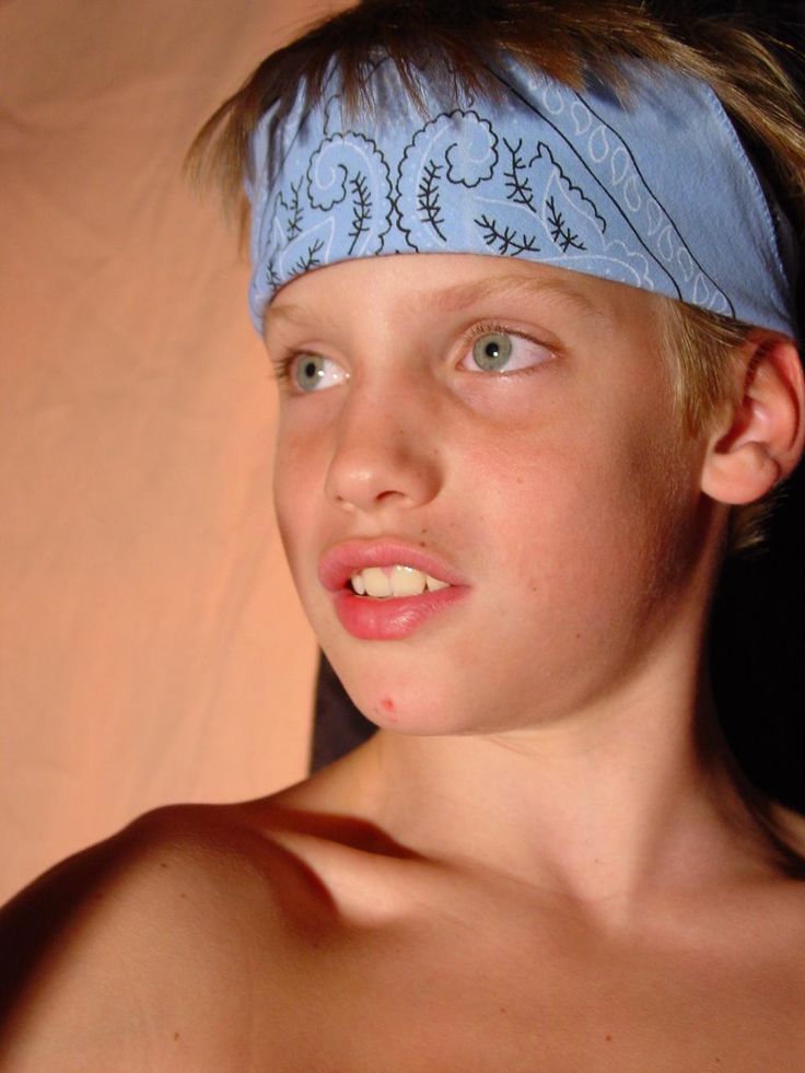 a young boy wearing a blue bandana and looking at the camera with an intense look on his face